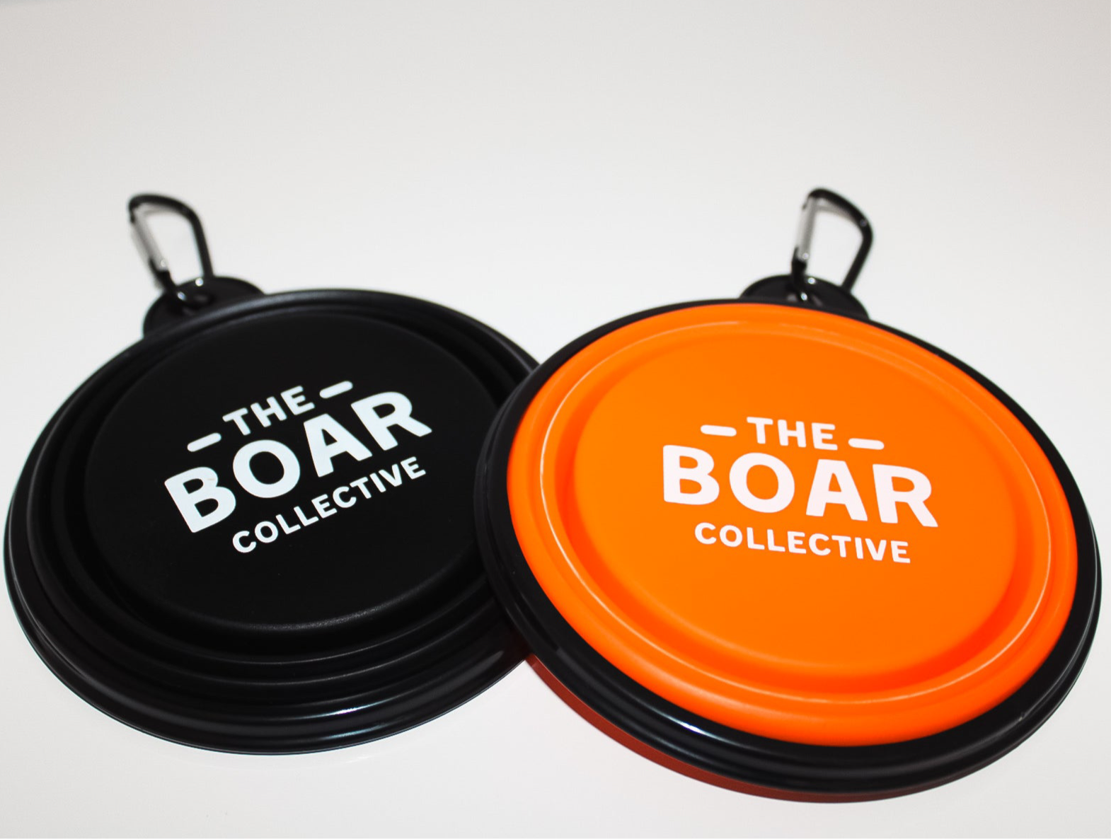The Boar Collective collapsible dog bowls in black and blaze orange with white printed logo and carabiner clips