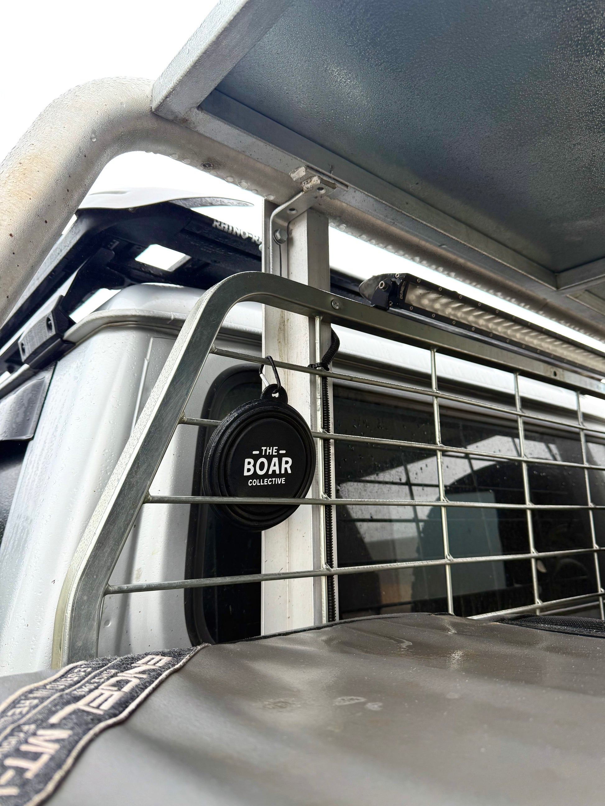 The Boar Collective round sticker displayed on a ute dog cage under canopy, showcasing rugged Aussie hunting rig setup