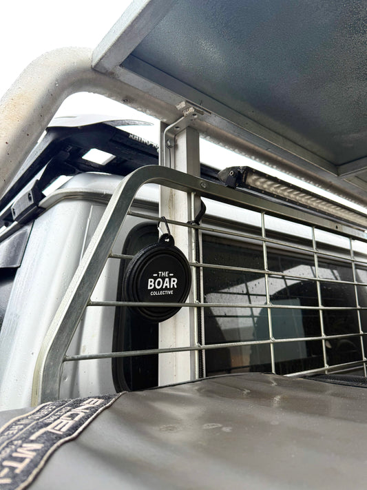 The Boar Collective round sticker displayed on a ute dog cage under canopy, showcasing rugged Aussie hunting rig setup