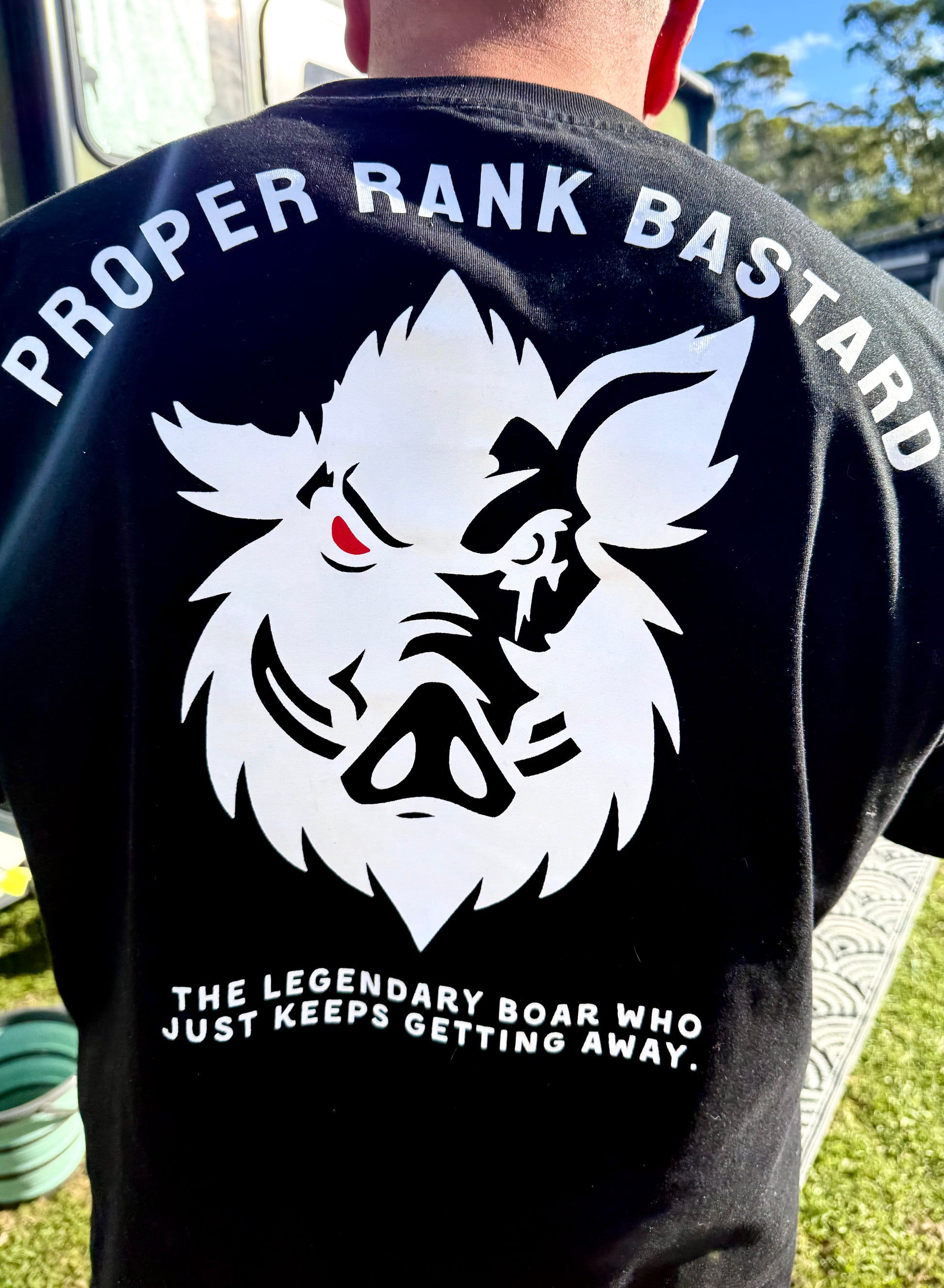 Proper Rank Bastard boar hunting black t-shirt back print with white boar logo and "The legendary boar who just keeps getting away" slogan — Boar Collective hunting apparel